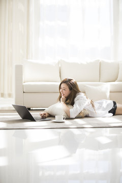 Cheerful young Chinese woman using laptop at home