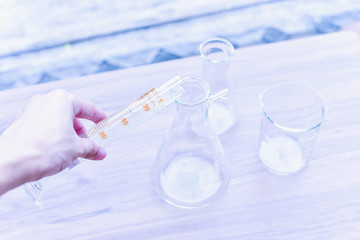 Hand Pouring Liquid Substance into a Glass Conical Flask with Measuring Cylinder