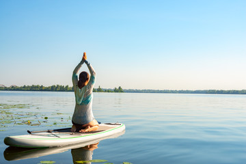 Female practicing yoga on a SUP board