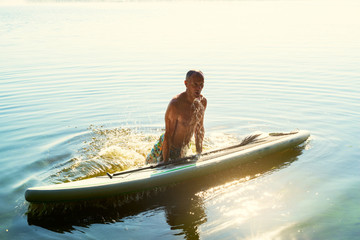 Joyful man is training on a SUP board and having fun