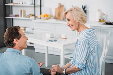 Fototapeta premium happy senior couple holding hands and smiling each other at home