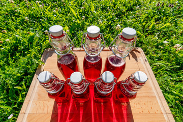 glass bottles of homemade cherry juice in the summer sun