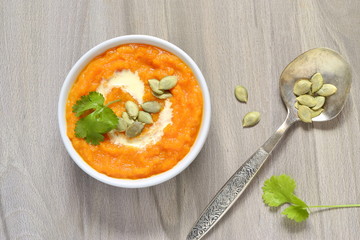 Pumpkin cream soup with cream and pumpkin seeds, top view