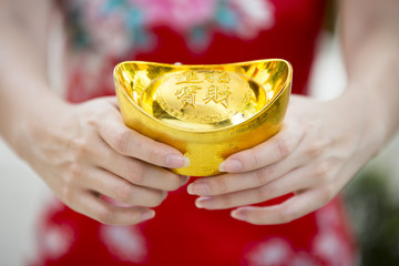 Hand holding gold ingot decoration commonly seen during lunar chinese new year