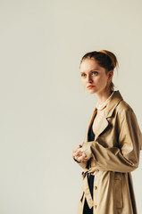 Studio portrait of young brunette girl wearing sexy cashmere coat standing on white wall background