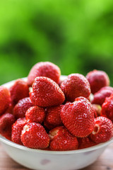 Fresh juicy large strawberry in a bowl close-up outdoors at the cottage