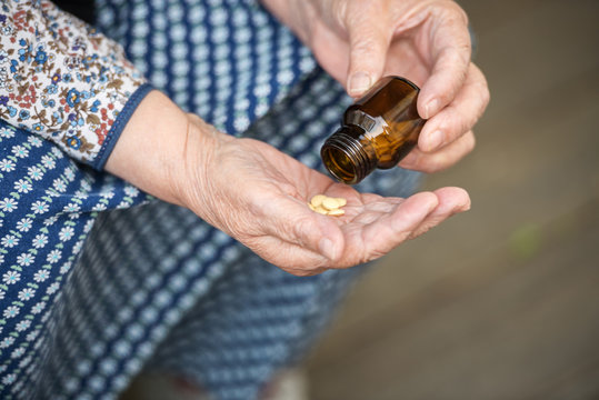 pills in the hands of an old lady closeup