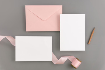 A wedding mock up concept. Wedding Invitation, envelopes, cards Papers on color background with ribbon and decoration. Top view, flat lay, copy space