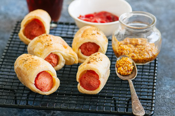 Pigs in a planket. Puff pastry rolls with sausages on a wire rack. Fast food or beer snack concept.