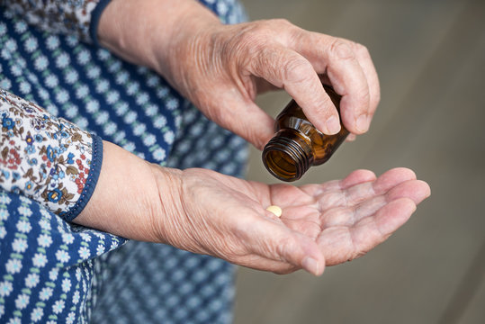 pills in the hands of an old lady closeup