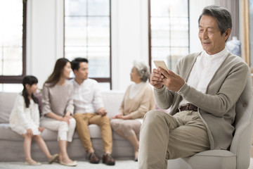 Senior Chinese man using smart phone at home