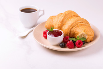 Coffee, fresh croissant with jam and berries for breakfast