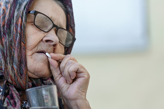  old woman takes pills, close-up