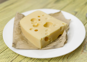 A piece of cheese with holes on a white plate.