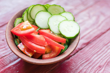 Salad of fresh tomatoes and cucumbers. Sliced tomatoes and cucumbers in a deep plate.