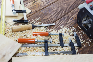 The composition of the clips, chisels, and chips on the desktop in the wood workshop.
