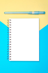 Flat lay design with blank on note book with pen on a blue and yellow background. Minimalist concept. Vertical version