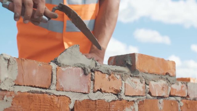 Close-up shut of Bricklayer working on a blue sky background