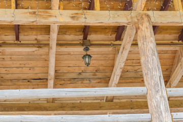 wooden ceiling of log house decorated garland and vintage lantern