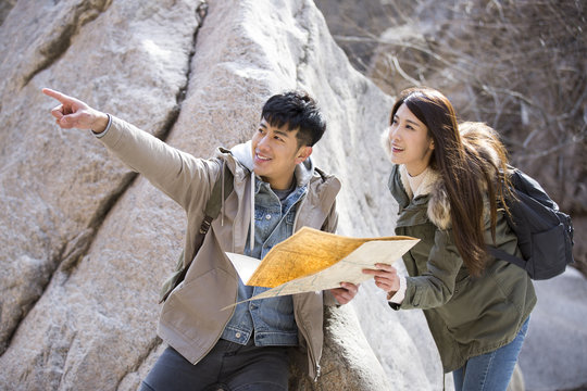 Happy young Chinese couple looking at a map outdoors
