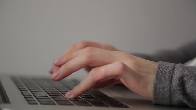 hands typing on computer, grey background.