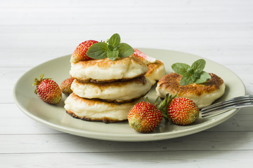 Curd pancakes with strawberries and mint on a plate