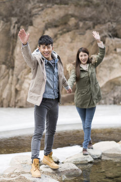 Happy young Chinese couple waving outdoors in winter