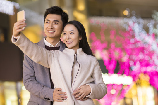 Cheerful young Chinese couple taking self portrait with smart phone