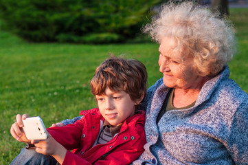A boy with a grandmother shoots Selfie on the phone outdoors