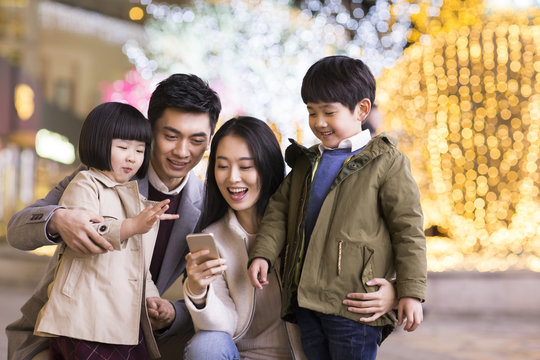 Cheerful young Chinese family using smart phone