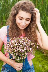 Beautiful woman with bouquet of pink flowers looking down, in summer