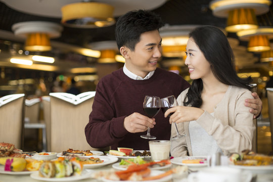 Cheerful young Chinese couple toasting with red wine