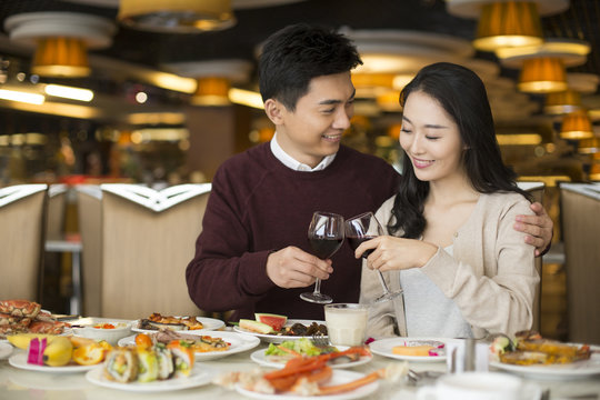 Cheerful young Chinese couple toasting with red wine
