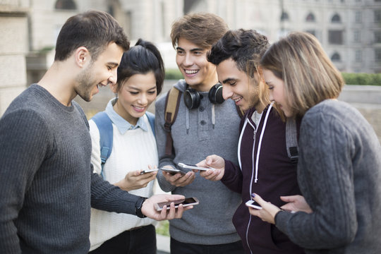Cheerful abroad students using smart phones on campus