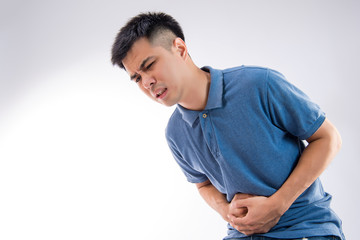 Man putting his hands for belly or stomach ache on white background