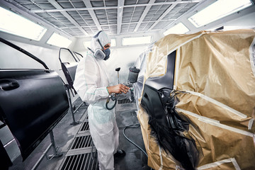 Painting the car in black color in the paint chamber on the service..