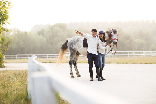 Cheerful young Chinese couple with horse 