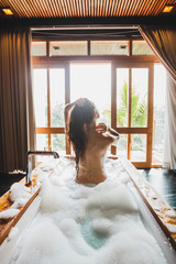 Slim beautiful girl enjoying in bath full of foam. Enjoying in hotel spa room