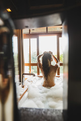 Obraz na płótnie Canvas Slim beautiful girl enjoying in bath full of foam. Enjoying in hotel spa room