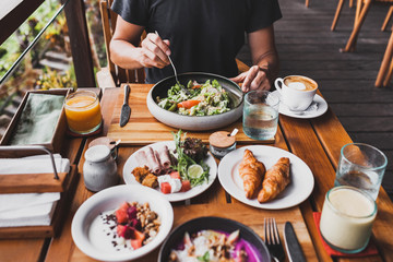 View from above on table with fresh breakfast. Man hands holding fork and knife