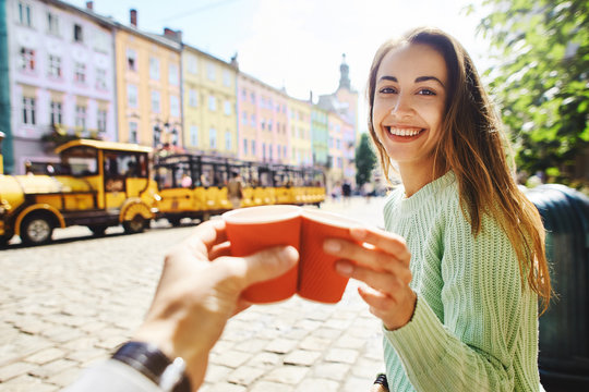 attractive happy smiling woman sitting in the center of old city with paper cup of coffee