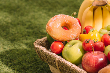 Picnic basket with food on green sunny lawn.