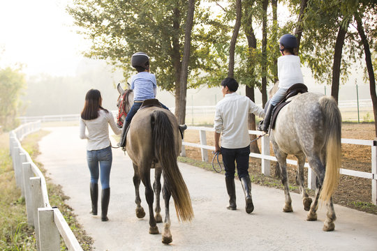 Cheerful young Chinese family riding horse