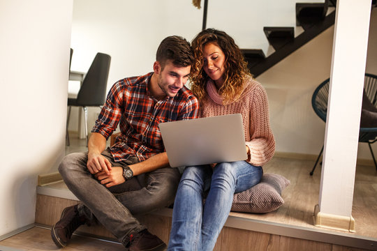 Young couple sitting in living room and using laptop.Shopping online.