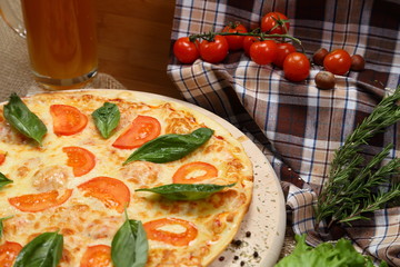 Pizza with tomato, cheese, salad, on a wooden stand closeup