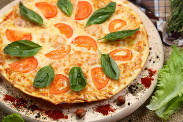 Pizza with tomato, cheese, salad, on a wooden stand closeup