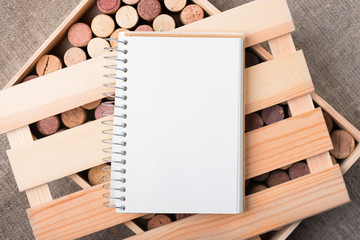 Wine cork stoppers in wooden box with open notebook Copy space Natural background