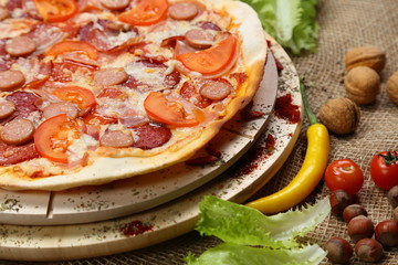 Pizza with sausages, tomato, smoked sausage, bacon, red pepper and cheese close-up