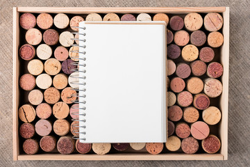 Wine cork stoppers in wooden box with open notebook Copy space Natural background
