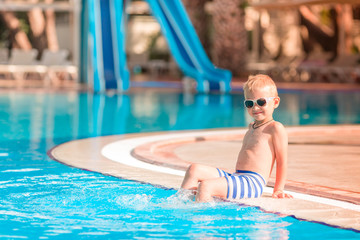 Naklejka premium Cute little boy sitting at the pool